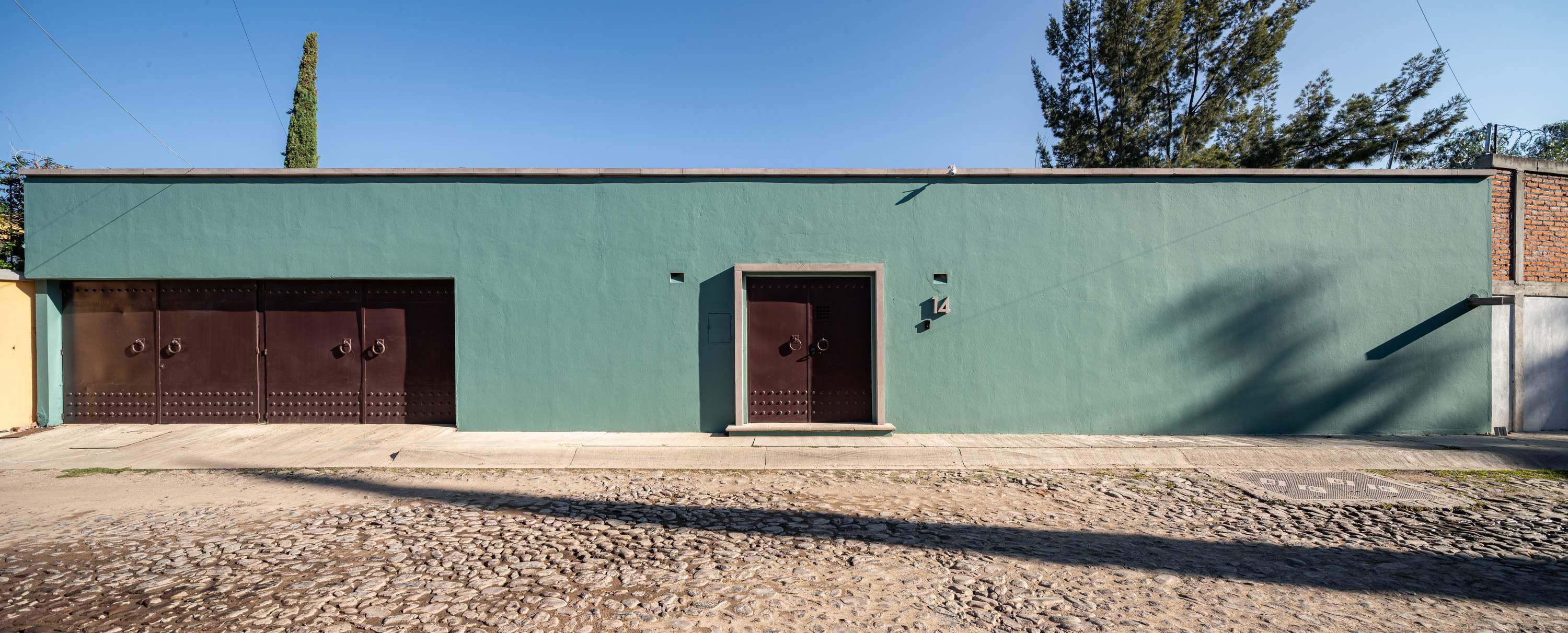 Teal-green stucco building and cobblestone street