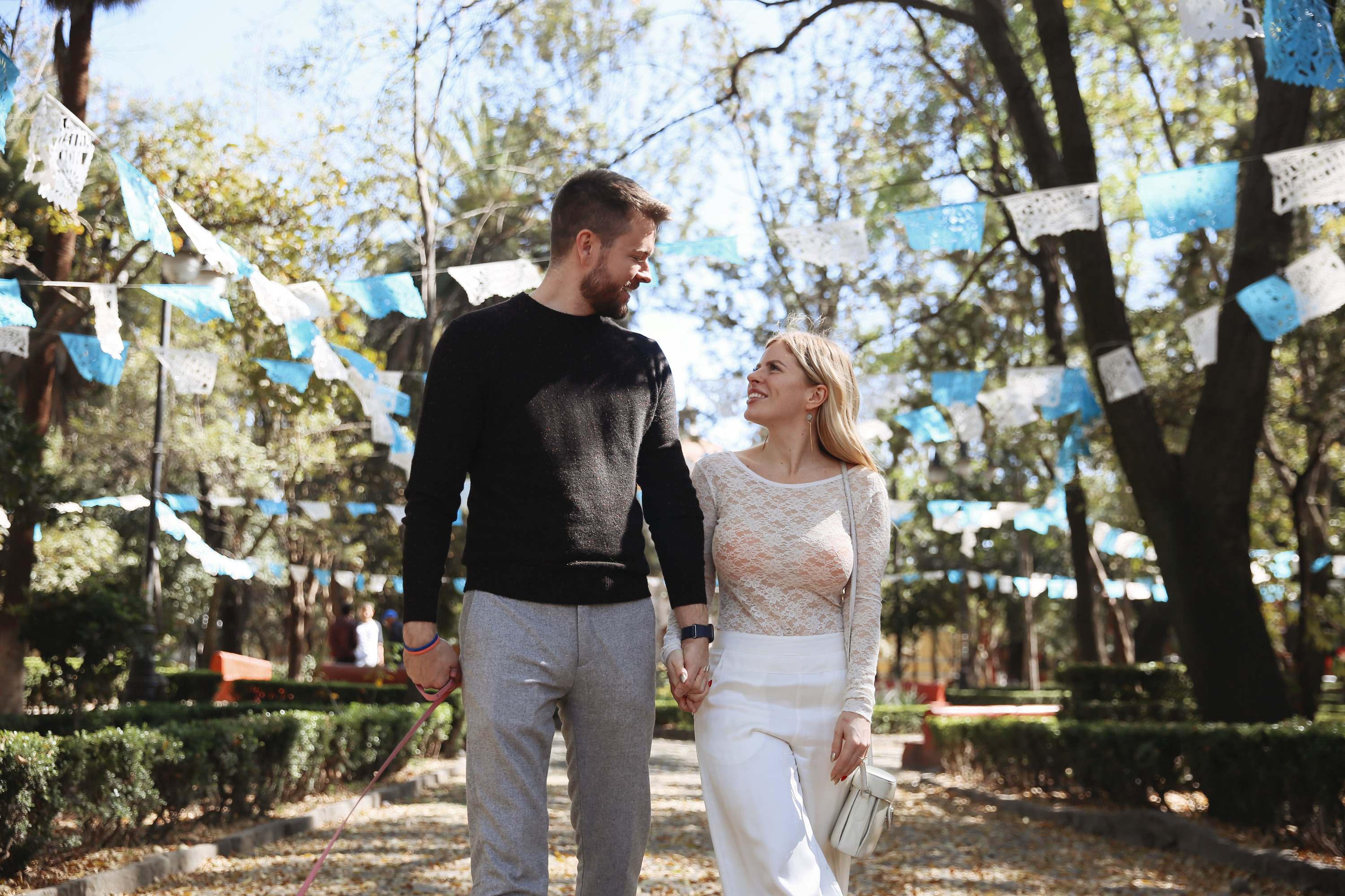 Benjamin Earley and Ioana Holt walking hand in hand through a park