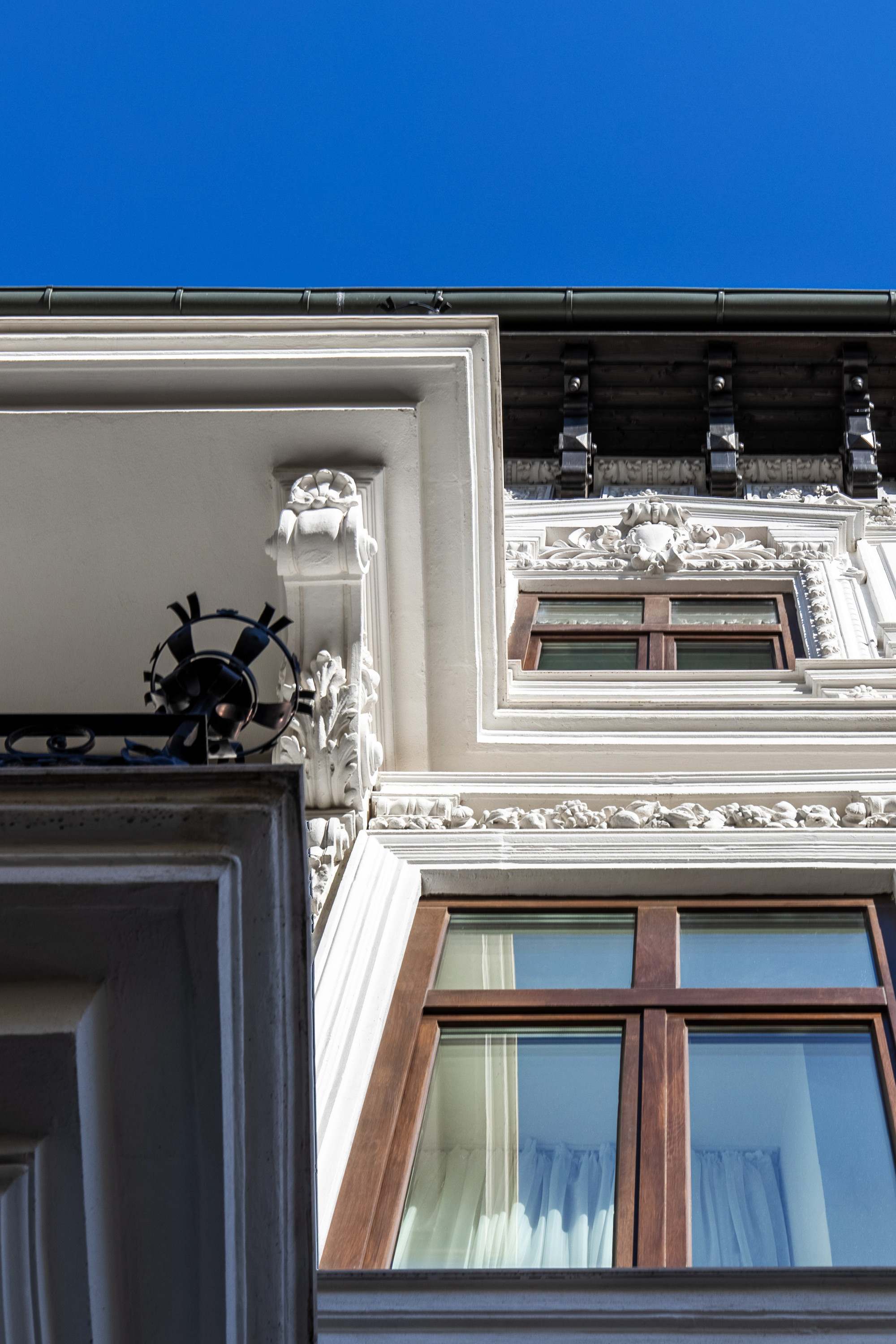HOLT Old Town in Bucharest, an ornate white facade with wooden windows against a blue sky