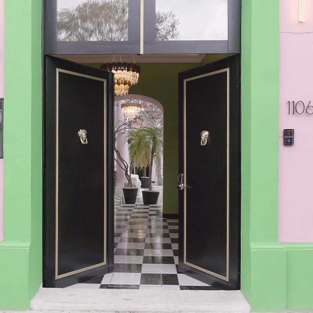 Open black doors of a HOLT hotel with a keypad entry panel on the wall beside them
