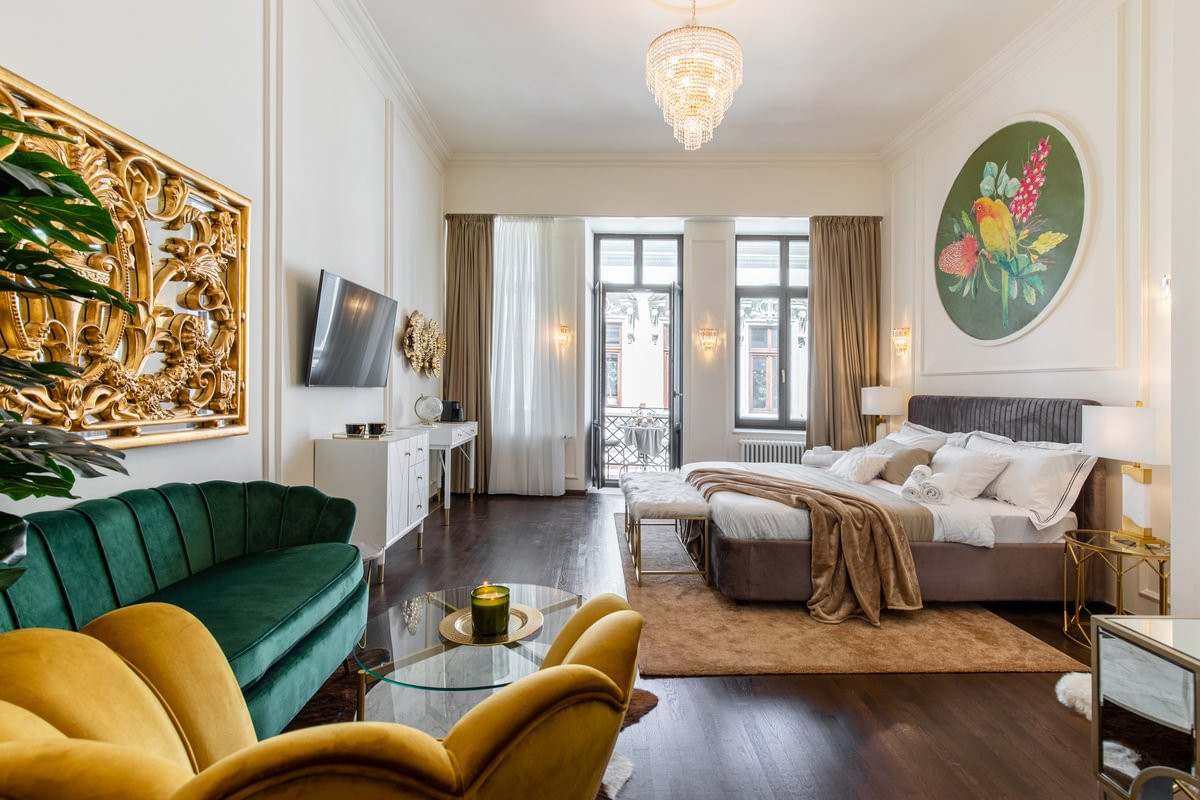 Guest room at HOLT Old Town in Bucharest with a green velvet sofa and tall windows