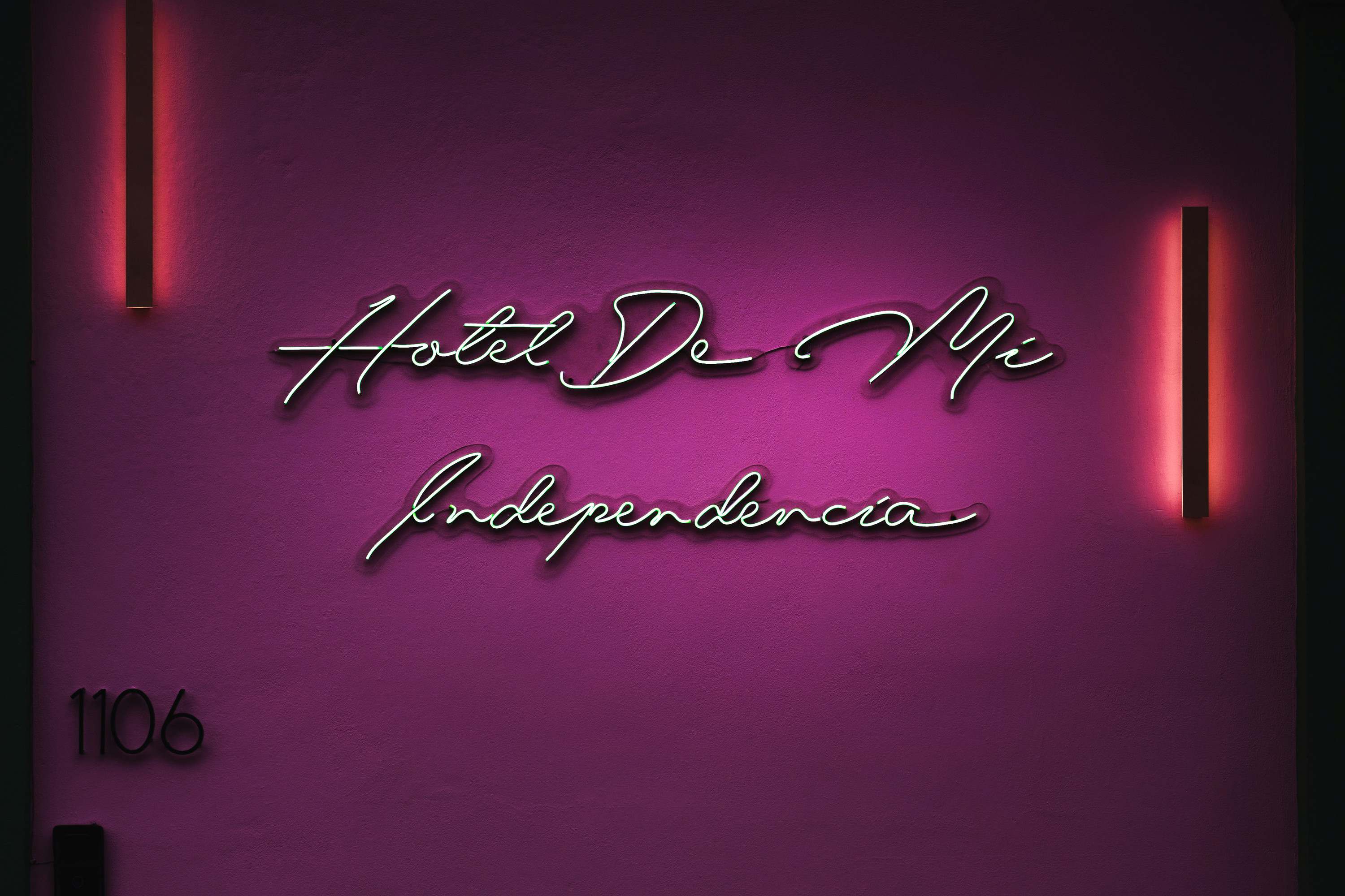 Neon sign reading Hotel De Mi Independencia on a magenta wall